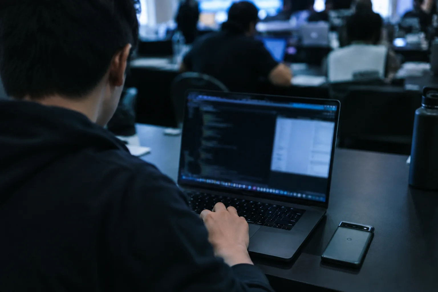 AI-generated image of a security researcher testing a smartphone beside a laptop at a cybersecurity competition.